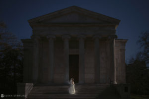 A bride is standing in front of Nassau Inn at night, on her wedding day.