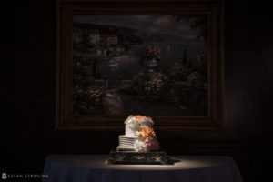 A Nassau Inn wedding cake sitting on a table in front of a painting.