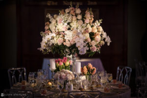 A table setting with white and pink flowers in a vase at a wedding reception at Nassau Inn.