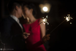 A wedding couple holding sparklers in the dark at Nassau Inn.