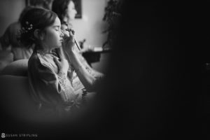 A little girl is getting her hair done at a wedding in a black and white photo at Loews Hotel Philly.
