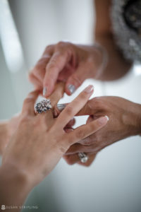 A woman is placing a wedding ring on another woman's hand at the Florentine Gardens estate.