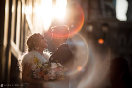 A bride and groom standing in front of the Loews Hotel at sunset on their wedding day in Philly.