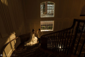 A bride and groom gracefully descend a grand staircase at the elegant Florentine Gardens estate on their wedding day.