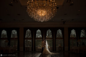 A bride and groom standing in front of a chandelier at Florentine Gardens, a picturesque wedding estate.