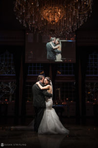 A bride and groom share their first dance in front of a large screen at the Florentine Gardens estate.