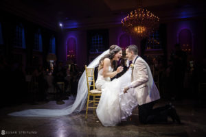 A bride and groom kneeling on a chair at a Wedding reception at Florentine Gardens.