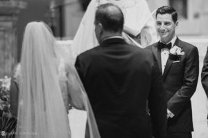 A bride and groom smiling at each other during their Pleasantdale Chateau wedding ceremony.