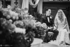 A bride and groom seated on the steps of the Pleasantdale Chateau after their wedding ceremony.