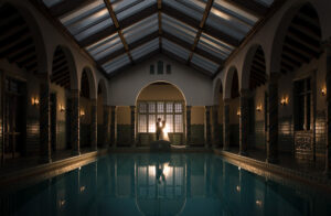 Pleasantdale Chateau, a wedding venue, features a stunning swimming pool situated within its architecturally elegant building adorned with graceful arches.