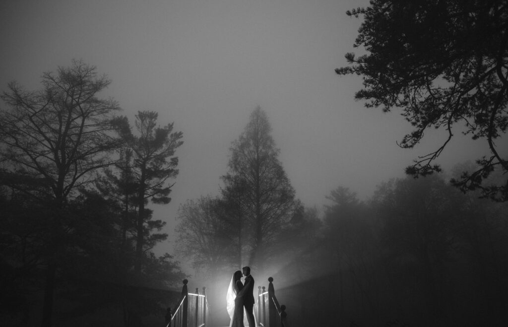 A wedding couple standing on a foggy bridge at Pleasantdale Chateau.