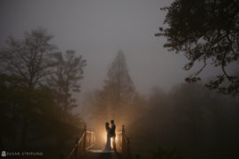 A wedding couple standing on a bridge at Pleasantdale Chateau in the fog.