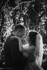 A black and white photo of a wedding couple in the woods near Whitby Castle.