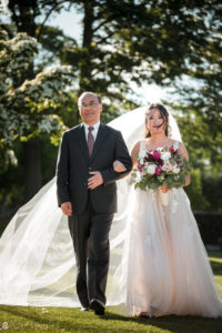 A bride walks down the aisle at her wedding with her father at Whitby Castle.