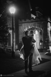 A bride and groom hugging in front of Whitby Castle on their enchanting wedding night.