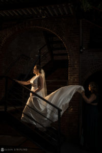 A bride is gracefully descending a grand staircase adorned with her exquisite wedding veil.