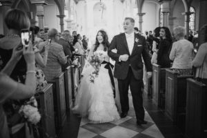 A wedding couple walking down the aisle of a St. Regis church.