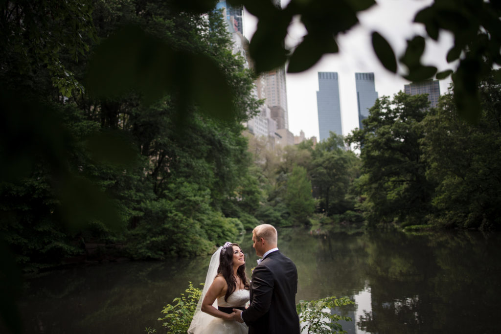 A St. Regis bride and groom standing next to a river in central park on their wedding day.