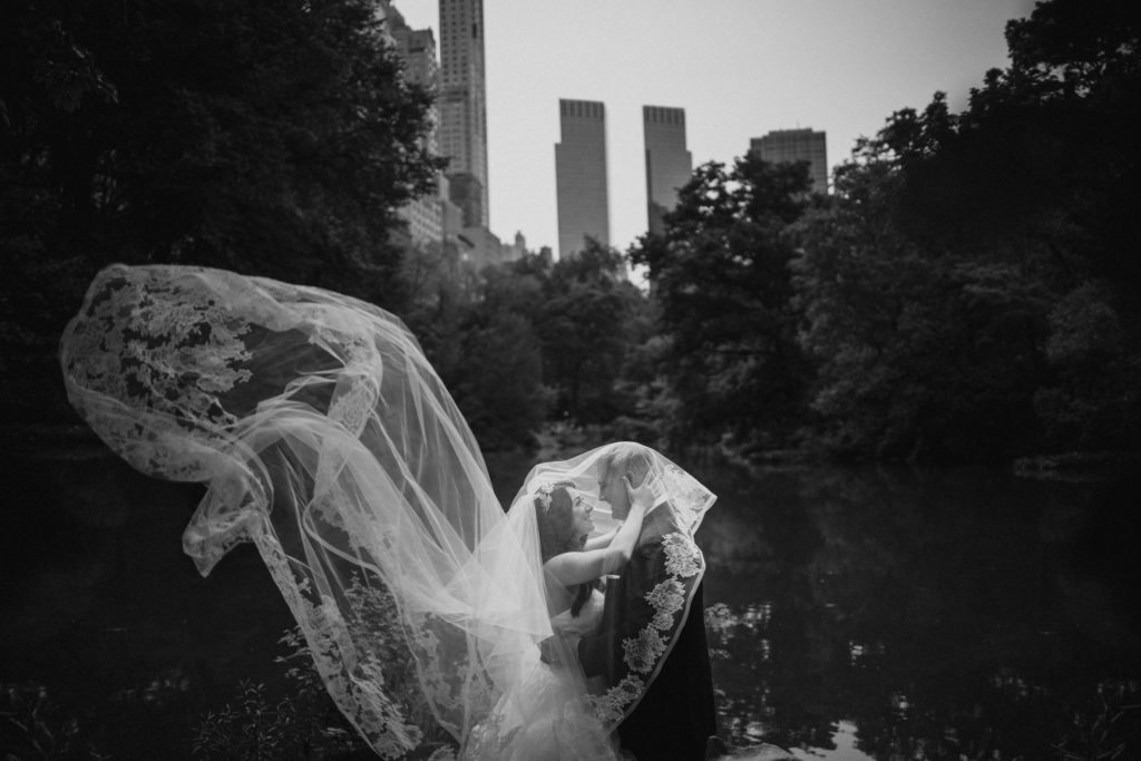 A wedding couple in front of a waterfall in central park.