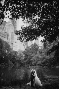 A bride and groom at the St. Regis in front of a pond in central park for their wedding.