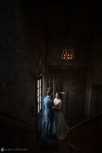 A bride and groom standing in a dimly lit room at the wedding reception.