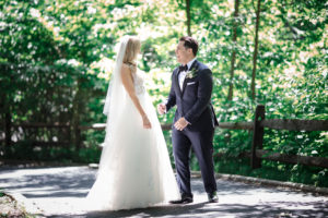 A bride and groom standing in the New York Botanical Gardens, surrounded by the lush woods as they celebrate their wedding day.