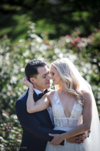 A bride and groom embracing in the New York Botanical Gardens on their wedding day.