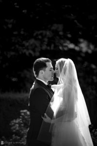 A bride and groom embrace in the Botanical Gardens of New York, captured in black and white.