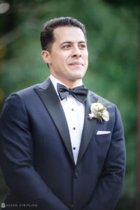 A groom in a tuxedo looking at the camera on his wedding day.