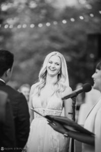 A bride smiles during her wedding ceremony at the New York Botanical Gardens.