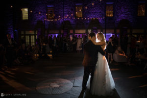 A bride and groom sharing their first dance in front of a New York castle.