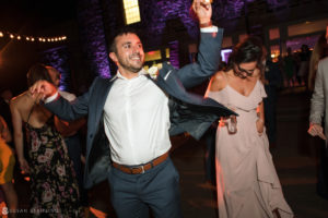 A man in a suit dancing at a New York wedding reception.
