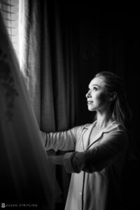 Black and white photo of a bride looking out of a window at the Yale Club on her wedding day.