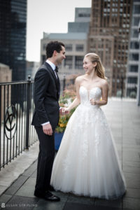 A newlywed couple standing on the rooftop of the Yale Club, overlooking the city on their wedding day.