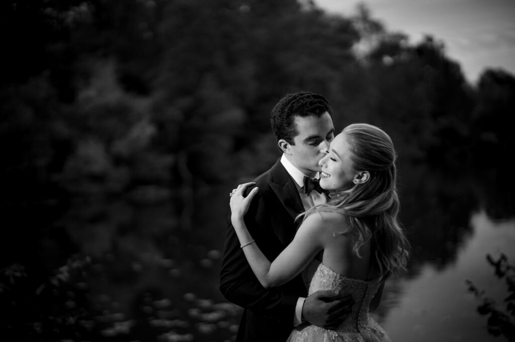 A bride and groom embracing in front of a river at their Yale wedding.