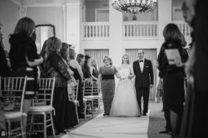 A wedding couple walking down the aisle at the Yale Club in a black and white photo.