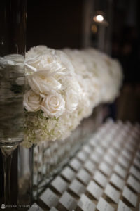 White roses in vases on a table at a wedding event at the Yale Club.