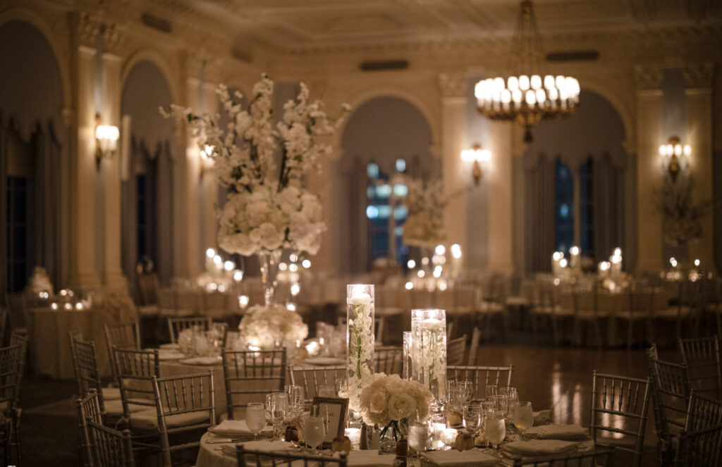 A Yale Club wedding reception in a large ballroom adorned with white tables and elegant candles.
