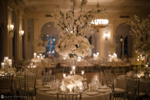 A Yale Club wedding reception in a ballroom with white flowers and candles.