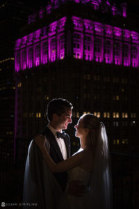 A wedding ceremony at Yale Club, with the bride and groom standing elegantly in front of a building at night.