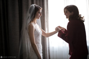 A bride and her mother shake hands in a Ritz Carlton hotel room.