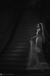 A bride is standing on the stairs at the Ritz Carlton in Philadelphia in a black and white photo.