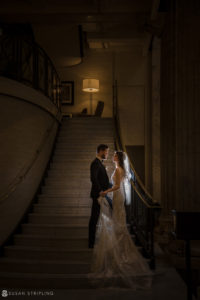 A bride and groom standing on the stairs at the Ritz Carlton in Philadelphia on their wedding night.