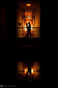 A Ritz Carlton bride and groom standing in front of a window at night during their Philadelphia wedding.
