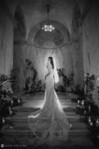 A bride in a wedding dress standing in a dark hallway at the Ritz Carlton.
