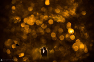 A romantic image of a couple kissing under a golden light at their Ritz Carlton wedding in Philadelphia.