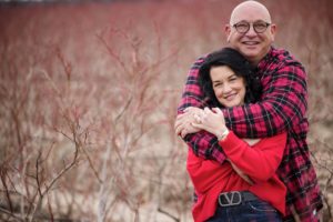 A man and woman hugging during a wedding at the Four Seasons Hotel Philadelphia at Comcast Center, surrounded by a stunning field of bushes.