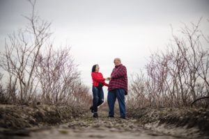 A couple standing on a dirt path in a field, capturing the essence of a romantic outdoor setting.