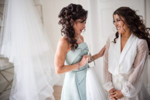 Two brides gazing at each other in a dressing room at the Estate at Florentine Gardens.
