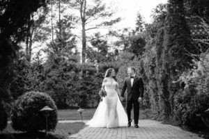 A beautiful black and white photo capturing the joyous moment of a bride and groom walking down a path at The Estate at Florentine Gardens.